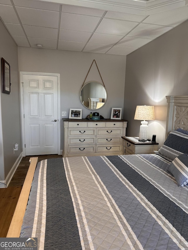 bedroom featuring a drop ceiling and dark wood-type flooring