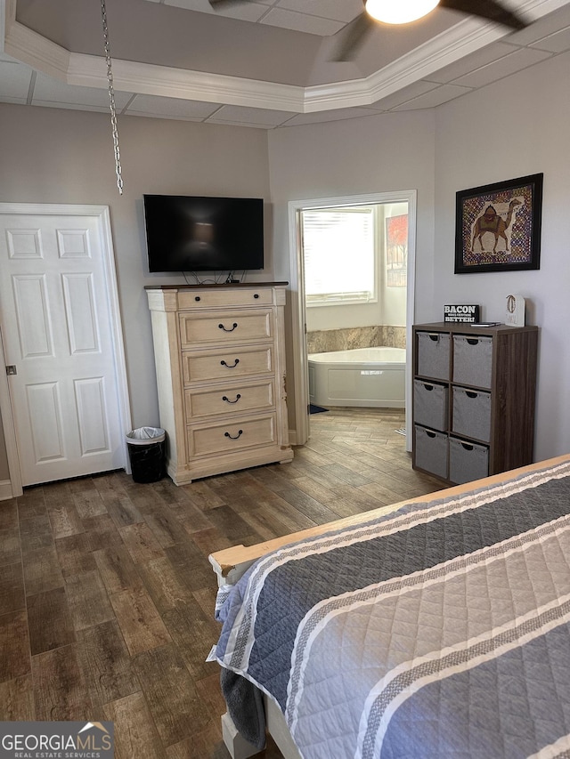 bedroom featuring a raised ceiling, connected bathroom, ornamental molding, and hardwood / wood-style flooring