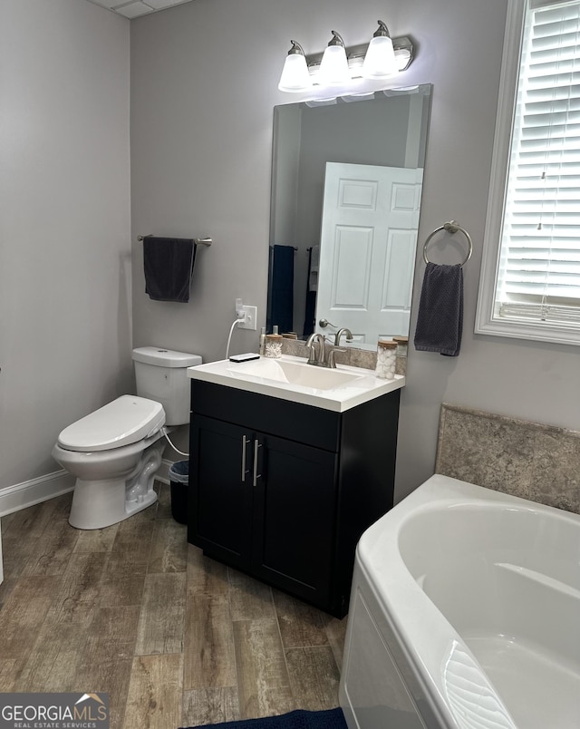 bathroom featuring hardwood / wood-style flooring, a washtub, toilet, and vanity