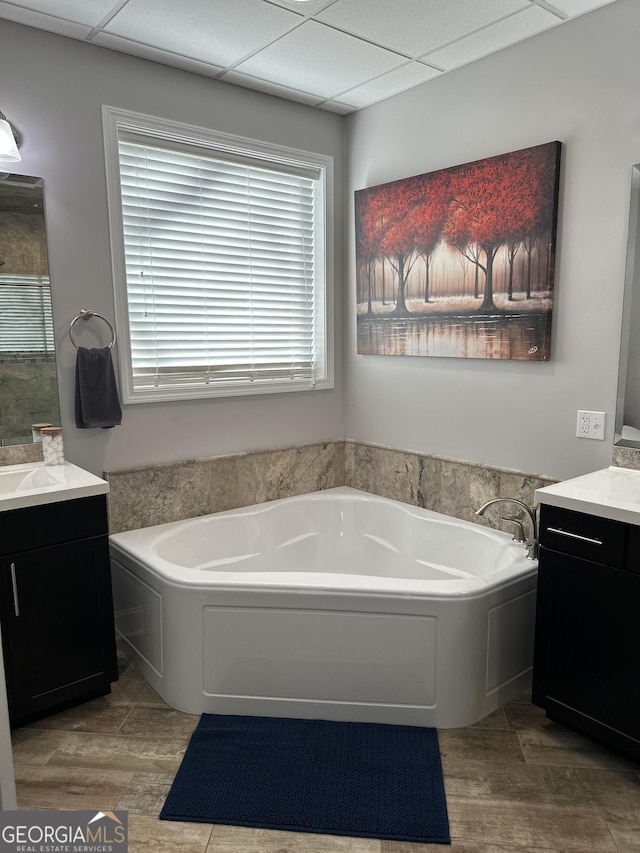 bathroom with a bath, a drop ceiling, vanity, and hardwood / wood-style floors