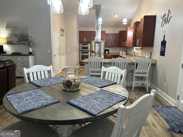 dining space featuring hardwood / wood-style floors and high vaulted ceiling