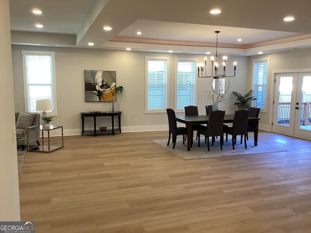 dining room featuring french doors, light hardwood / wood-style flooring, a notable chandelier, and a tray ceiling