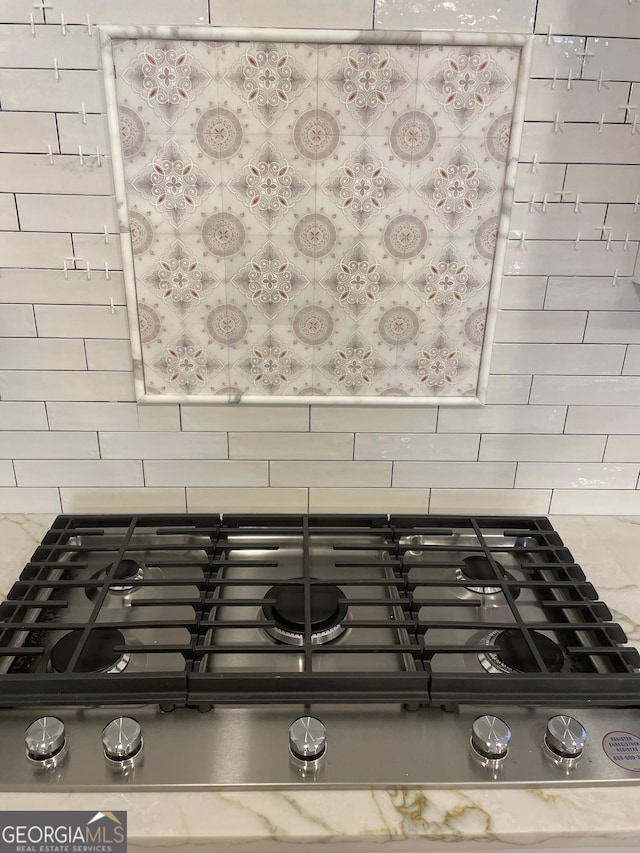 details featuring gas cooktop, light stone countertops, and decorative backsplash