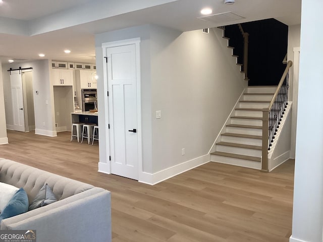 stairs with wood-type flooring and a barn door