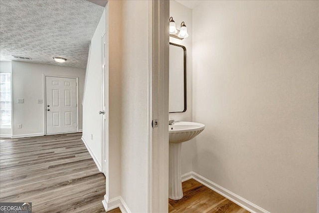 bathroom with wood-type flooring and a textured ceiling