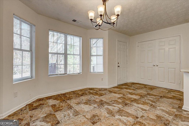 unfurnished dining area with a chandelier, a textured ceiling, and plenty of natural light