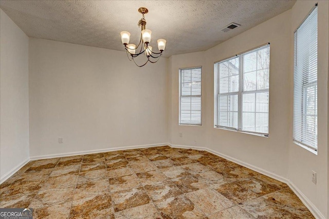 spare room with a chandelier and a textured ceiling