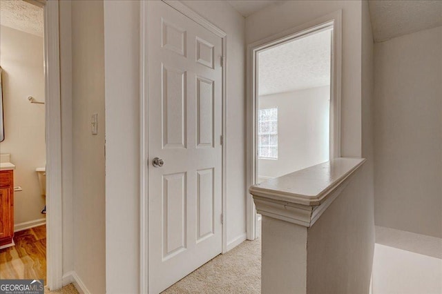 corridor featuring a textured ceiling and light wood-type flooring