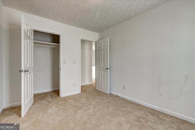 unfurnished bedroom with a textured ceiling, light colored carpet, and a closet