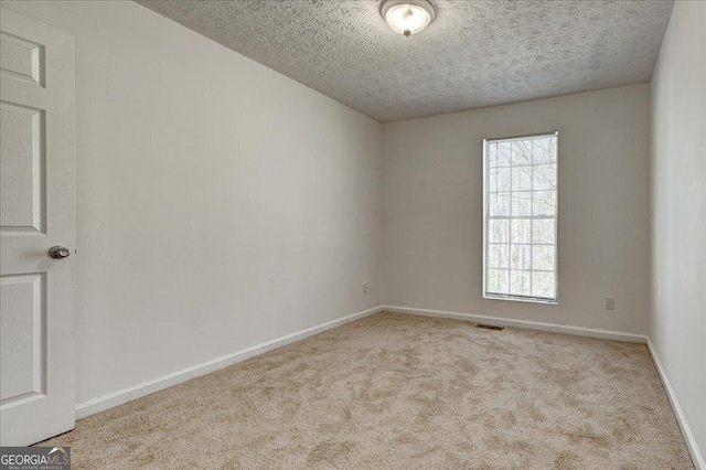 unfurnished room with light carpet and a textured ceiling