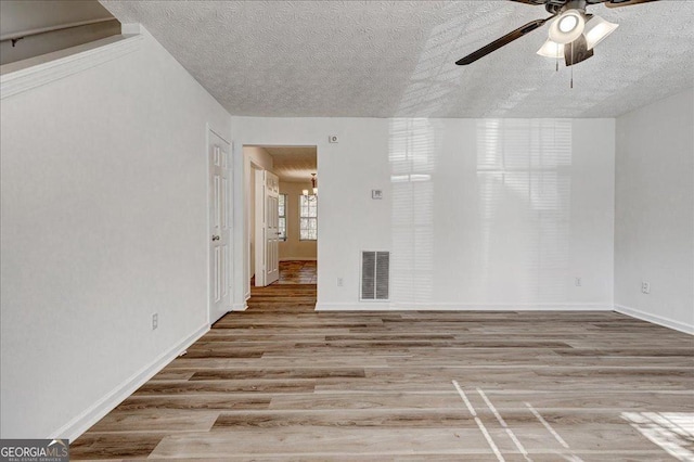 unfurnished room featuring ceiling fan with notable chandelier, a textured ceiling, and light hardwood / wood-style flooring