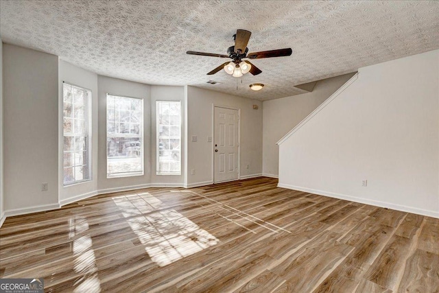 interior space featuring hardwood / wood-style floors, ceiling fan, and a textured ceiling