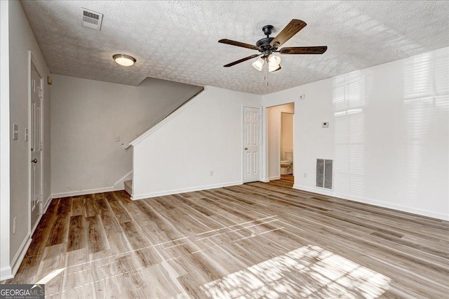 unfurnished living room with ceiling fan, a textured ceiling, and light hardwood / wood-style flooring