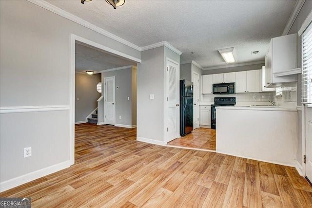 kitchen with black appliances, light hardwood / wood-style floors, white cabinetry, and ornamental molding