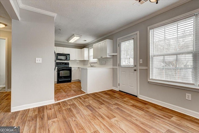 kitchen featuring a textured ceiling, crown molding, black appliances, white cabinets, and light hardwood / wood-style floors