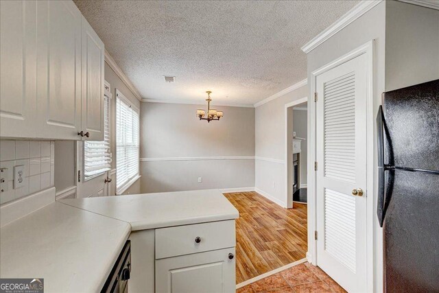 kitchen with black refrigerator, crown molding, light hardwood / wood-style flooring, white cabinets, and hanging light fixtures