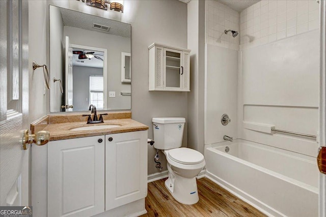 full bathroom with vanity, tiled shower / bath combo, ceiling fan, hardwood / wood-style floors, and toilet