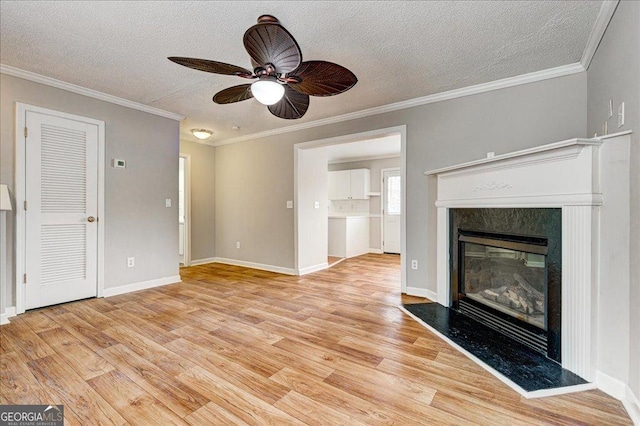 unfurnished living room featuring ornamental molding, a textured ceiling, ceiling fan, a premium fireplace, and light hardwood / wood-style floors