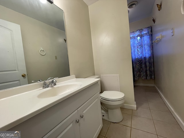 bathroom with toilet, vanity, and tile patterned floors