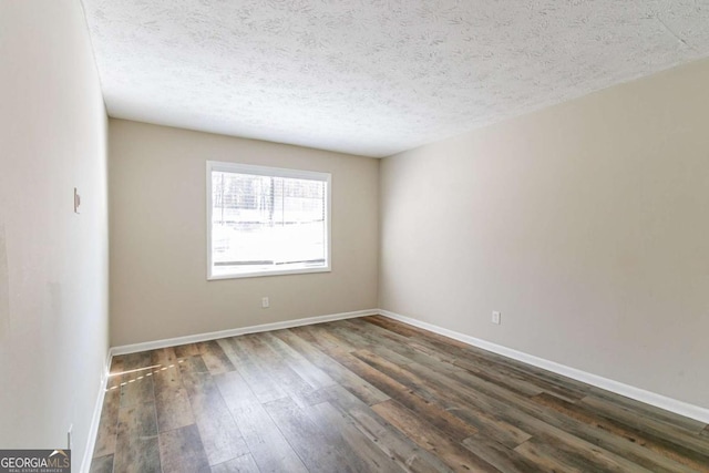 empty room with a textured ceiling and dark hardwood / wood-style flooring