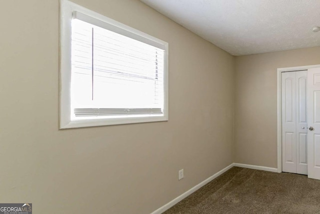 unfurnished bedroom with dark carpet, a textured ceiling, and a closet