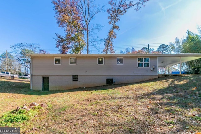 rear view of house with a lawn, central air condition unit, and a carport