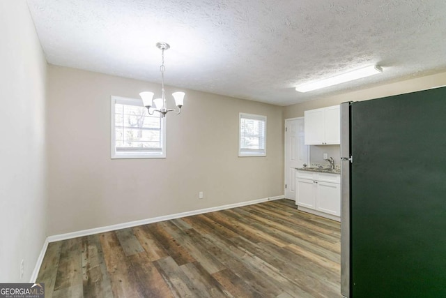 unfurnished dining area featuring a healthy amount of sunlight, dark wood-type flooring, and an inviting chandelier