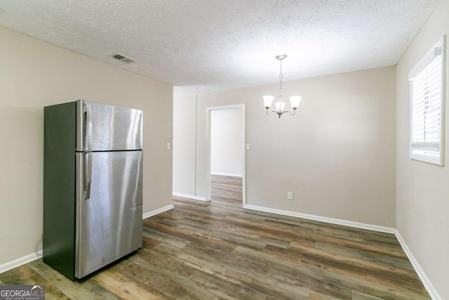 kitchen with a chandelier, stainless steel refrigerator, and dark wood-type flooring