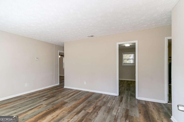 empty room featuring dark hardwood / wood-style flooring and a textured ceiling