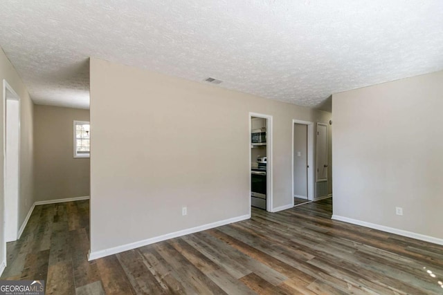 empty room with a textured ceiling and dark hardwood / wood-style floors