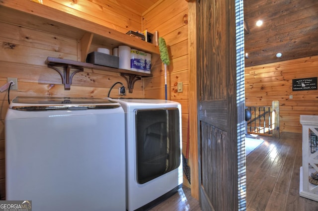 washroom with wood walls, washer and clothes dryer, and dark hardwood / wood-style floors