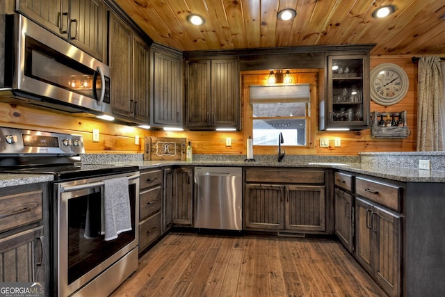 kitchen featuring stone countertops, dark hardwood / wood-style flooring, dark brown cabinets, and appliances with stainless steel finishes