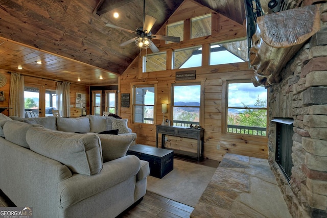 living room with french doors, a stone fireplace, wood walls, wood-type flooring, and wood ceiling