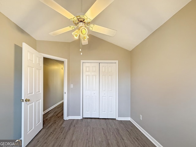 unfurnished bedroom with lofted ceiling, a closet, ceiling fan, and dark wood-type flooring