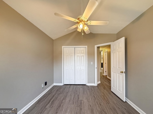 unfurnished bedroom featuring lofted ceiling, ceiling fan, a closet, and dark hardwood / wood-style floors