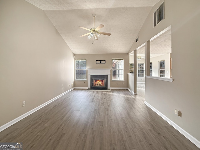 unfurnished living room with ceiling fan, high vaulted ceiling, dark hardwood / wood-style floors, and a textured ceiling