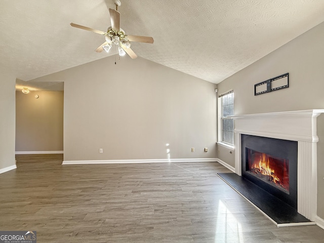 unfurnished living room with a textured ceiling, ceiling fan, wood-type flooring, and vaulted ceiling