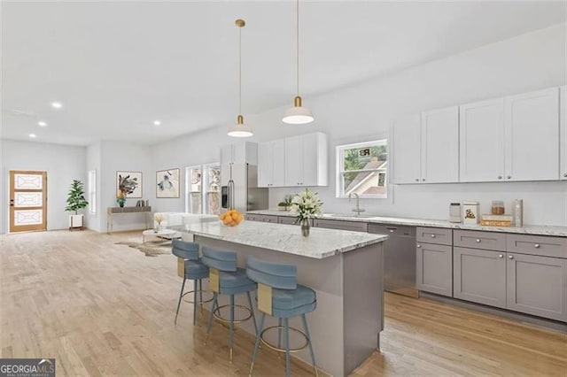 kitchen with a kitchen bar, pendant lighting, light wood-type flooring, and stainless steel appliances