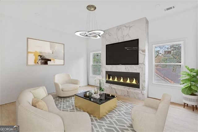 living room featuring light hardwood / wood-style floors, a fireplace, and an inviting chandelier