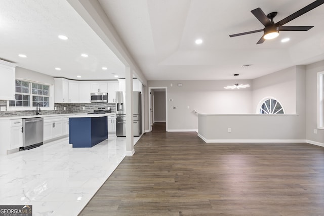 kitchen featuring wood-type flooring, white cabinets, stainless steel appliances, and a kitchen island