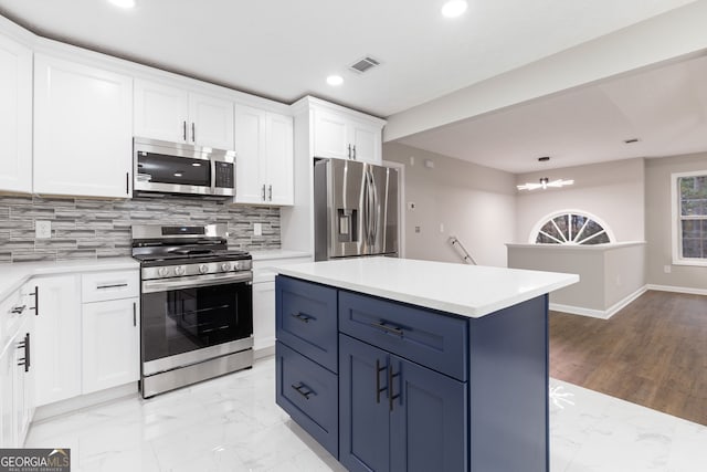 kitchen featuring appliances with stainless steel finishes, tasteful backsplash, an inviting chandelier, a center island, and white cabinetry