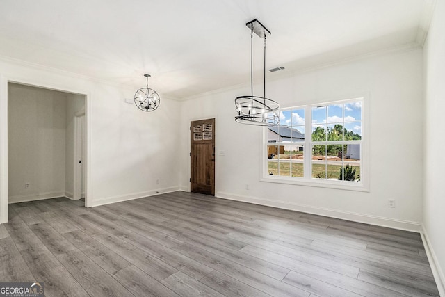 unfurnished dining area with wood-type flooring, an inviting chandelier, and crown molding