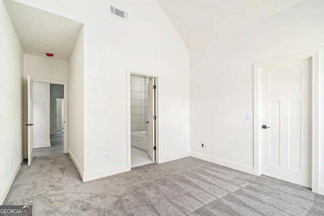 unfurnished bedroom with connected bathroom, light carpet, and lofted ceiling