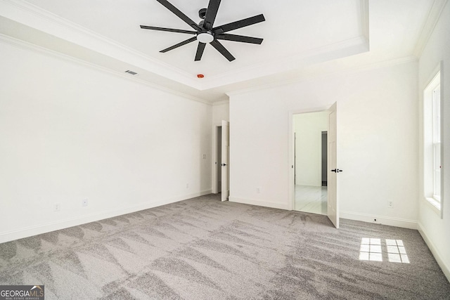 unfurnished bedroom with ceiling fan, a raised ceiling, carpet floors, and crown molding