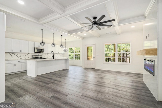 kitchen with appliances with stainless steel finishes, dark hardwood / wood-style flooring, ceiling fan, a center island with sink, and white cabinetry