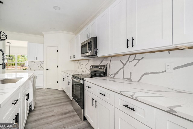 kitchen with light stone countertops, light wood-type flooring, appliances with stainless steel finishes, tasteful backsplash, and white cabinetry