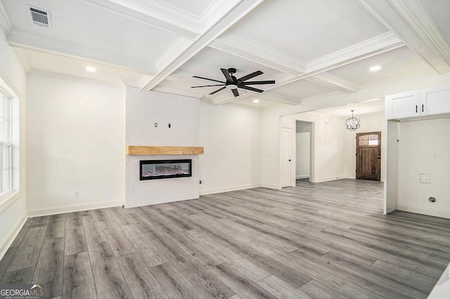 unfurnished living room featuring beamed ceiling, ceiling fan with notable chandelier, a large fireplace, and light hardwood / wood-style flooring