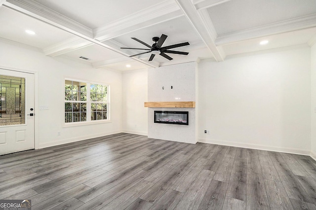 unfurnished living room featuring ceiling fan, a large fireplace, beamed ceiling, and wood-type flooring