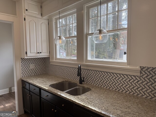 kitchen with backsplash, light stone countertops, sink, and white cabinets