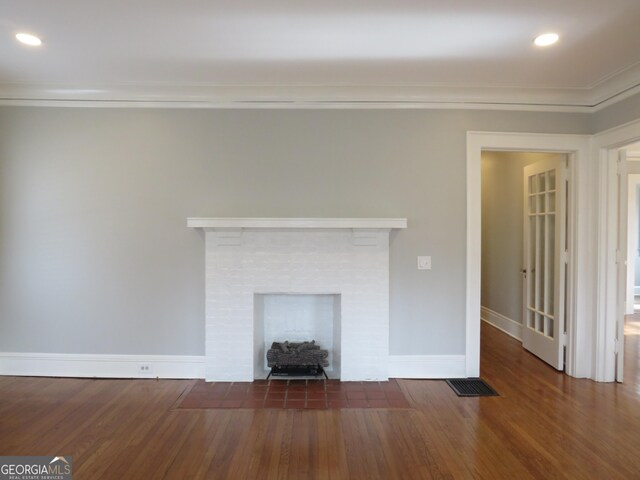 unfurnished living room with a fireplace, crown molding, and dark wood-type flooring